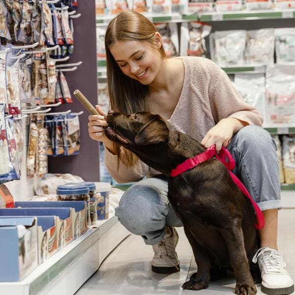 A beautiful girl in the store chooses a toy for her dog